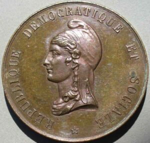 Copper coin featuring a left-facing female bust wearing a headscarf; rim inscription reads 'REPUBLIC DEMOCRATIQU E ET SOCIALE' with a small star beneath.