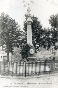 Monument in Béziers: tall column with a bust on top and a kneeling figure at the base, fenced by iron railing.